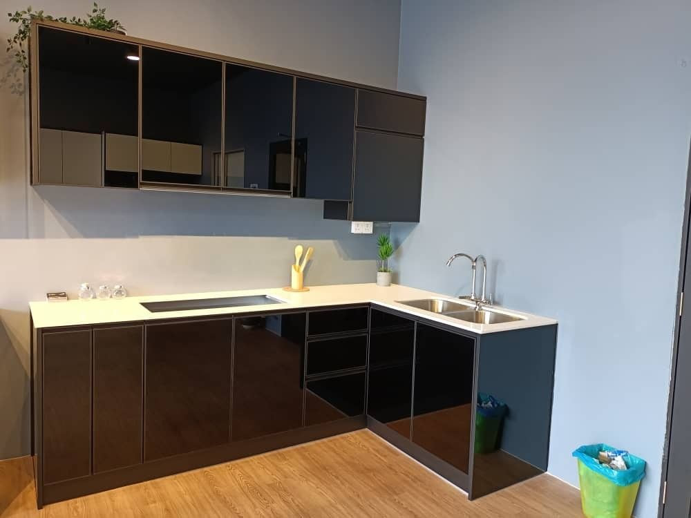 A dark bronze and black kitchen against a blue wall, with timber-look flooring and a hob run.