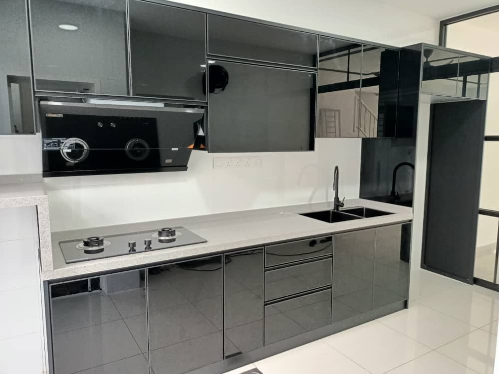 A dark gloss kitchen with a black cooker hood, a hob, a white worktop and a washing-machine bay.